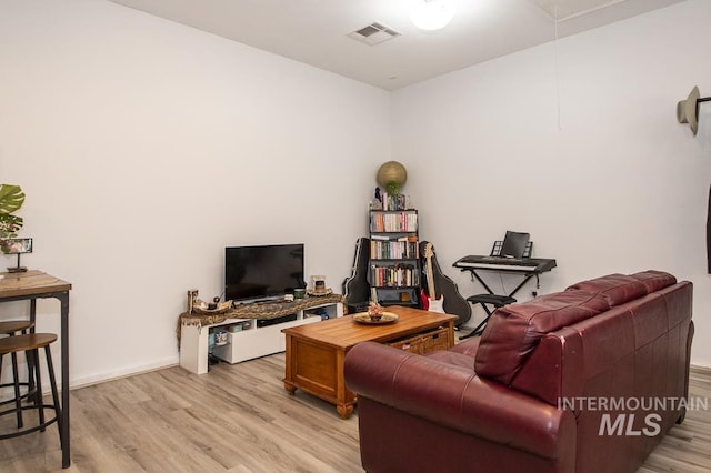 living area featuring light wood-type flooring, attic access, visible vents, and baseboards