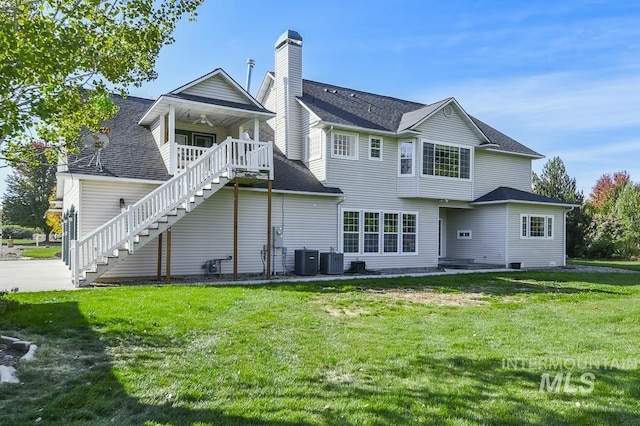 rear view of property with stairs, cooling unit, and a yard