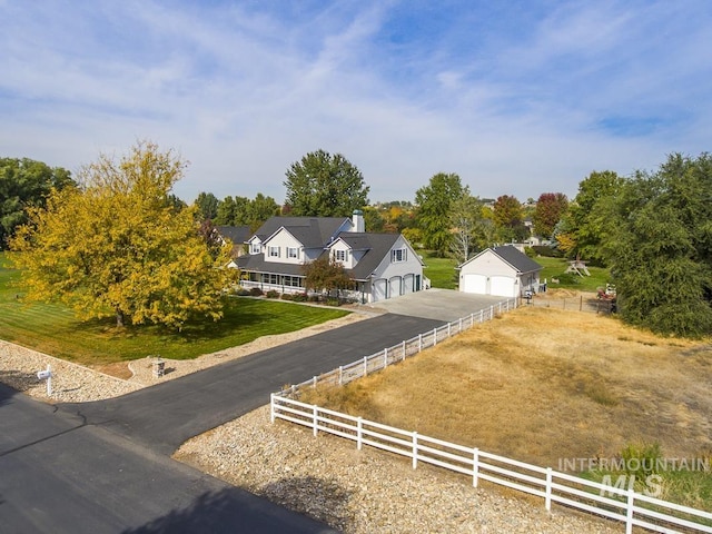 view of front facade featuring a front lawn, a rural view, fence, and a detached garage