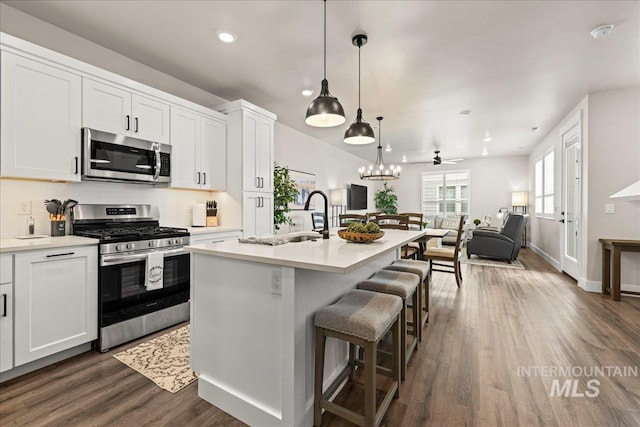 205 S Ripplerock Ln, Star, ID 83669 - kitchen featuring appliances with stainless steel finishes, a sink, dark wood-style flooring, open floor plan, and a kitchen bar