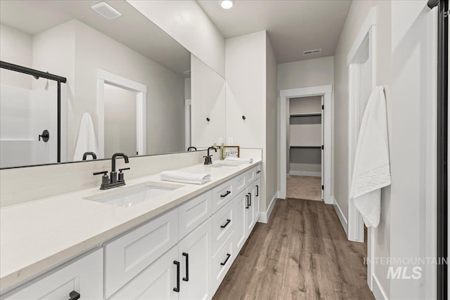 205 S Ripplerock Ln, Star, ID 83669 - bathroom featuring baseboards, wood finished floors, double vanity, a walk in closet, and a shower