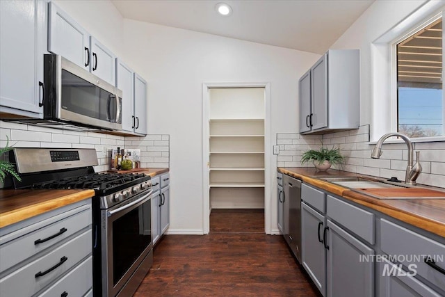 kitchen with butcher block counters, gray cabinetry, sink, stainless steel appliances, and dark hardwood / wood-style flooring