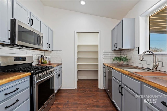 kitchen featuring butcher block countertops, sink, lofted ceiling, and stainless steel appliances