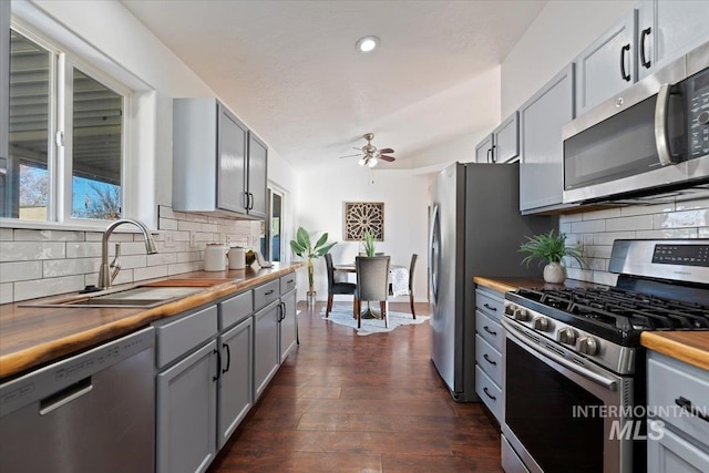 kitchen featuring gray cabinetry, stainless steel appliances, butcher block counters, and sink