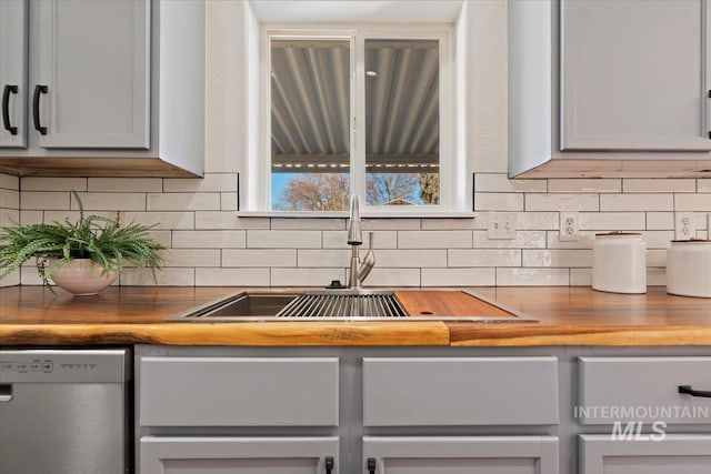 kitchen with gray cabinetry, sink, wooden counters, white dishwasher, and decorative backsplash