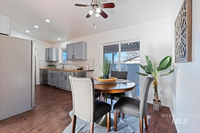 dining room featuring lofted ceiling, ceiling fan, dark wood-type flooring, and sink