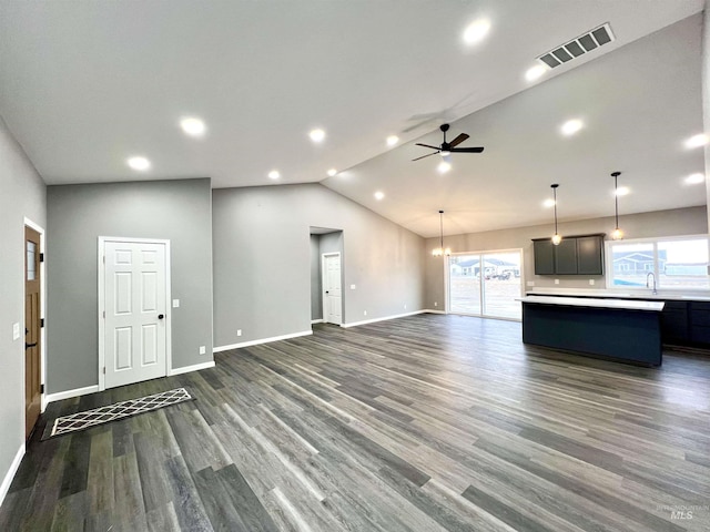 unfurnished living room with sink, ceiling fan with notable chandelier, high vaulted ceiling, and dark hardwood / wood-style floors