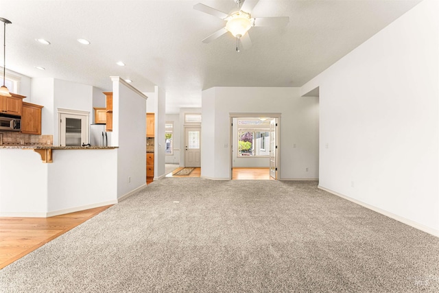 unfurnished living room featuring ceiling fan, light carpet, baseboards, and recessed lighting
