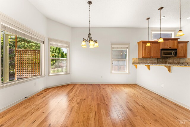 unfurnished dining area featuring baseboards, a chandelier, and light wood-style floors
