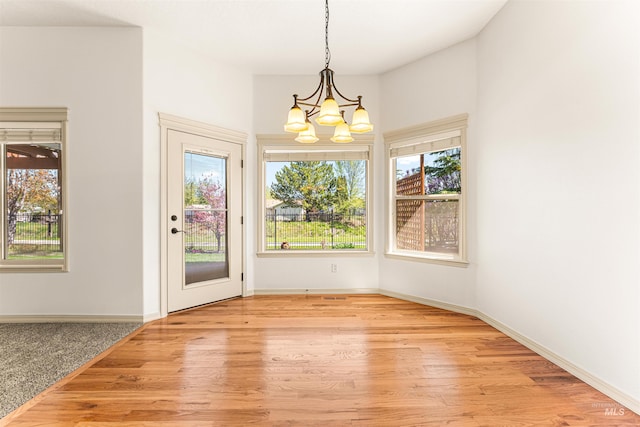 unfurnished dining area featuring wood finished floors, a wealth of natural light, and a chandelier