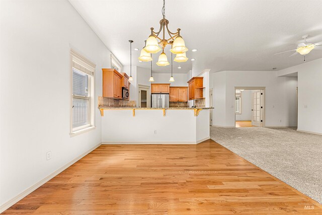 interior space with baseboards, light wood-style flooring, and ceiling fan with notable chandelier
