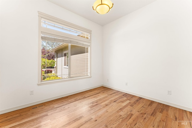 empty room featuring baseboards, wood finished floors, and visible vents