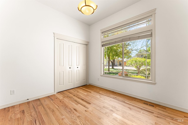 unfurnished bedroom featuring visible vents, baseboards, wood finished floors, and a closet