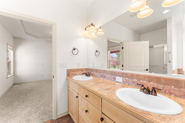 bathroom with double vanity, visible vents, a stall shower, and a sink