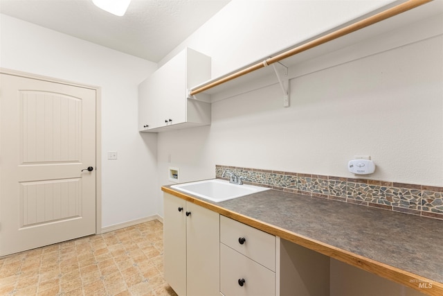laundry area with baseboards, a sink, washer hookup, and cabinet space