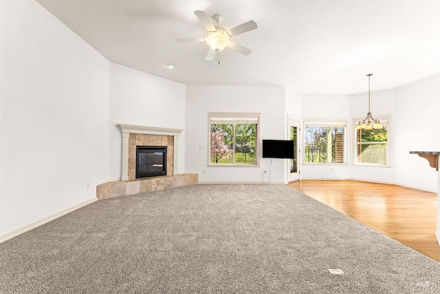 unfurnished living room featuring carpet floors, baseboards, a fireplace, and a ceiling fan