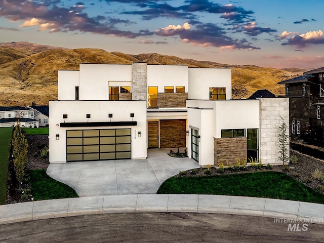 2528 S Linnet Pl, Boise, ID 83716 - contemporary home featuring an attached garage, concrete driveway, a mountain view, stone siding, and stucco siding