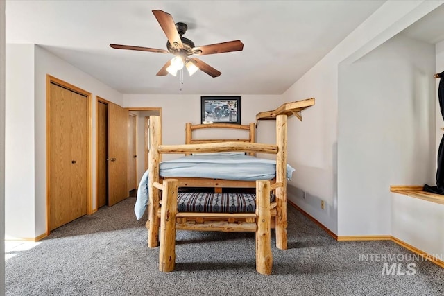 bedroom with carpet floors, a ceiling fan, baseboards, and two closets