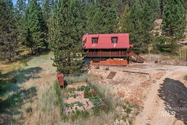 exterior space featuring a forest view, fence, a wooden deck, and stairs