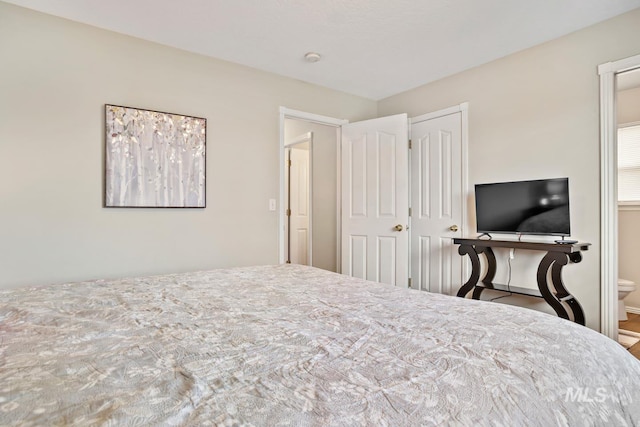 bedroom with connected bathroom and baseboards