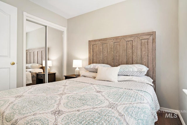 bedroom featuring a closet, wood finished floors, and baseboards