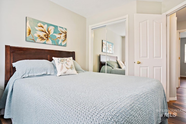 bedroom featuring a closet, dark wood-type flooring, and baseboards