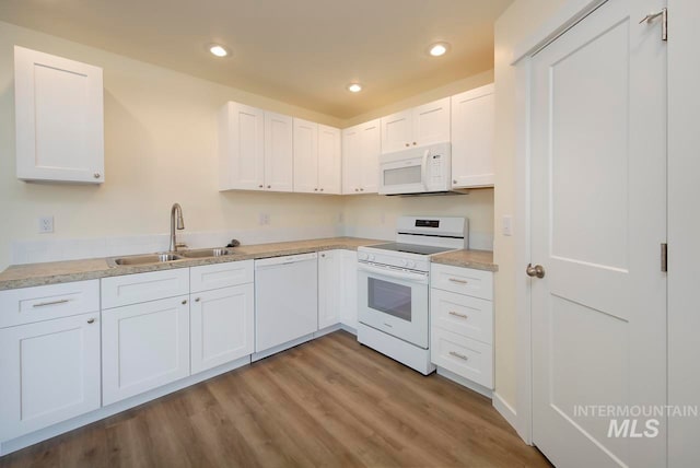 kitchen with sink, white cabinets, light hardwood / wood-style flooring, and white appliances