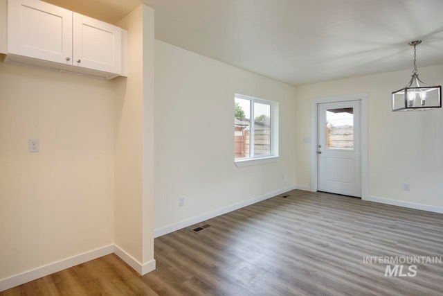 unfurnished dining area featuring light hardwood / wood-style floors and a chandelier