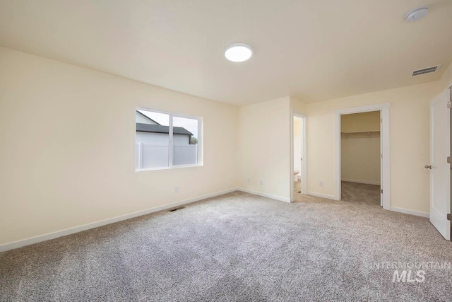 unfurnished bedroom with a spacious closet, carpet floors, and a closet