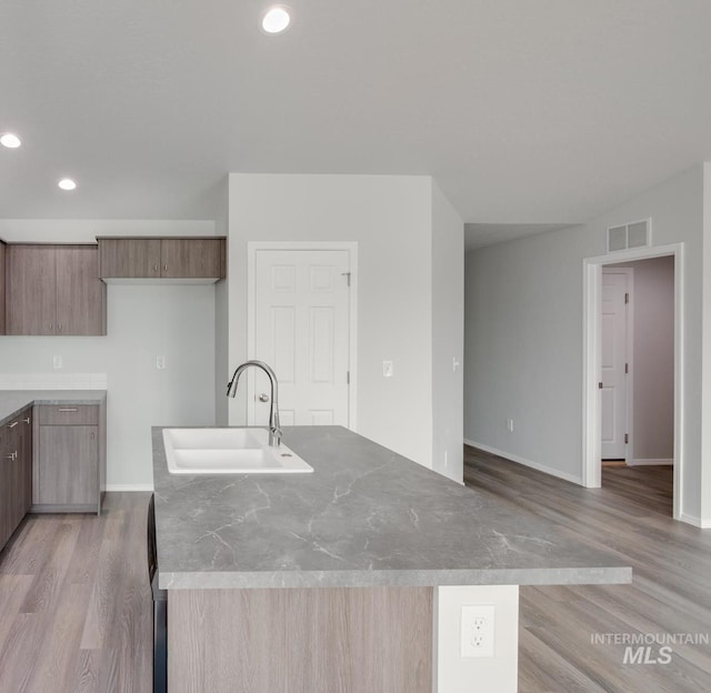 kitchen featuring a center island with sink, light hardwood / wood-style floors, and sink