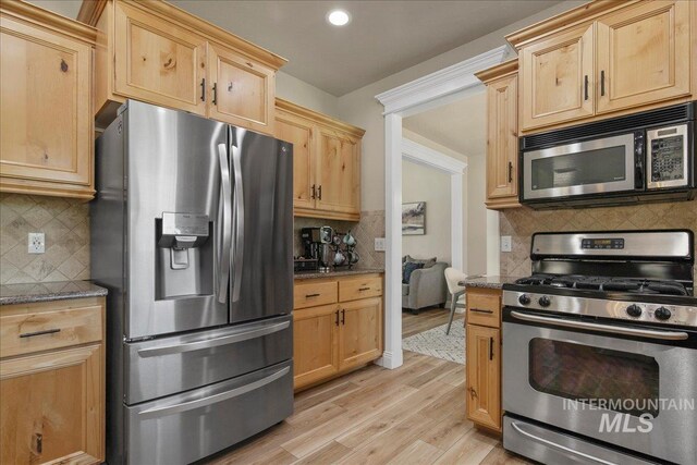 kitchen featuring stainless steel appliances, tasteful backsplash, light wood finished floors, dark stone counters, and recessed lighting