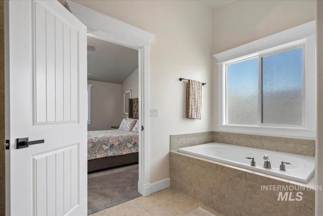 ensuite bathroom with tile patterned floors, a bath, and baseboards