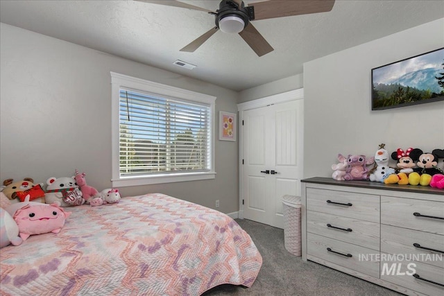 carpeted bedroom with ceiling fan, baseboards, and a textured ceiling