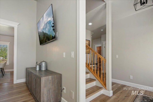 corridor with stairs, baseboards, wood finished floors, and recessed lighting