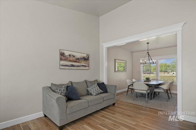 living area with a chandelier, baseboards, and light wood-type flooring