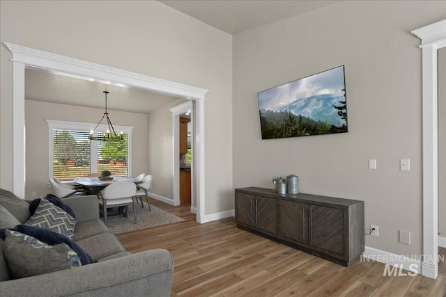 living room featuring a chandelier, light wood-style flooring, and baseboards