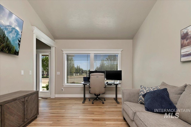 home office featuring light wood-style flooring, lofted ceiling, and baseboards
