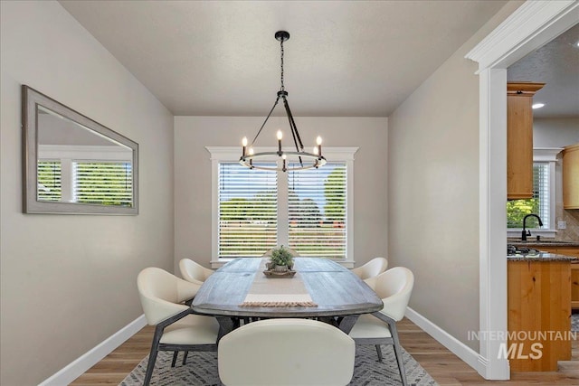 dining space with a chandelier, light wood-style flooring, and baseboards