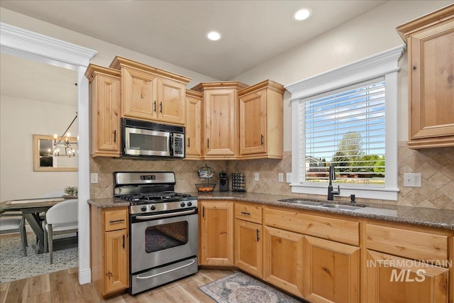 kitchen featuring stainless steel appliances, a sink, light wood finished floors, light brown cabinetry, and recessed lighting