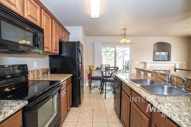 kitchen featuring light stone countertops, sink, black appliances, light tile patterned floors, and decorative light fixtures