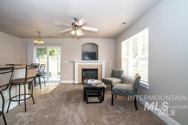 carpeted living room featuring ceiling fan with notable chandelier