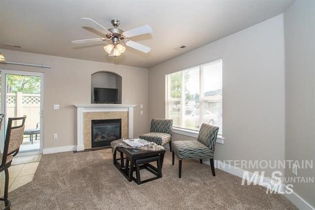 sitting room featuring a tile fireplace, light colored carpet, plenty of natural light, and ceiling fan