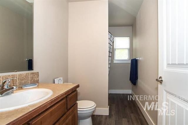 bathroom featuring toilet, vanity, lofted ceiling, and hardwood / wood-style flooring