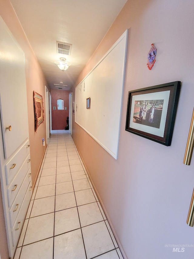 hallway featuring light tile patterned flooring, visible vents, and baseboards