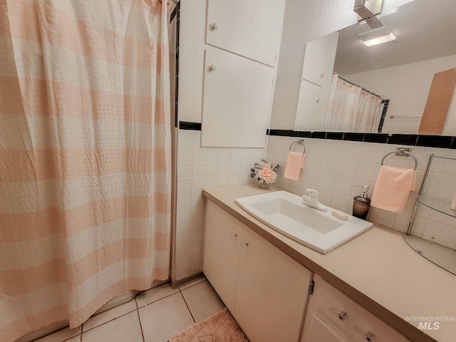 bathroom with curtained shower, tile patterned flooring, vanity, and tile walls