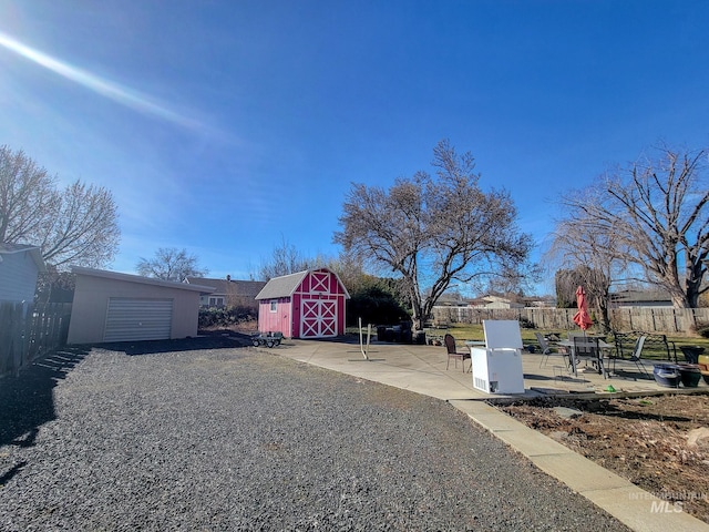 view of yard featuring gravel driveway, fence, a patio, and an outbuilding