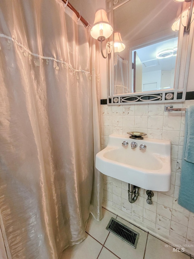 full bath with tile walls, visible vents, backsplash, a sink, and tile patterned flooring