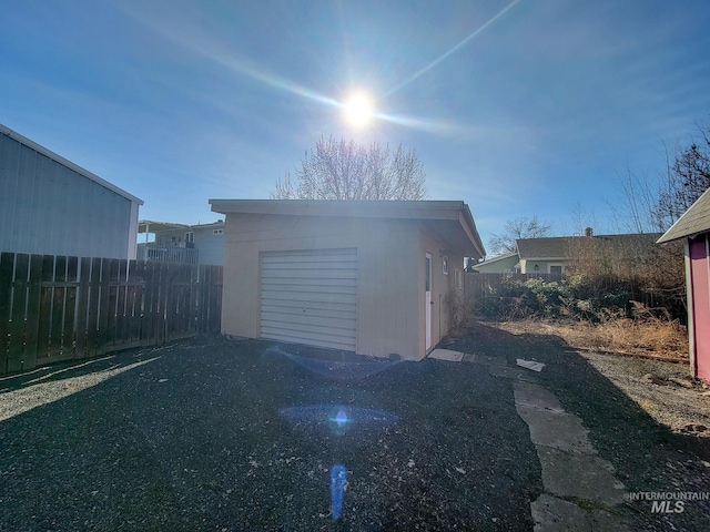 garage featuring fence and a storage unit