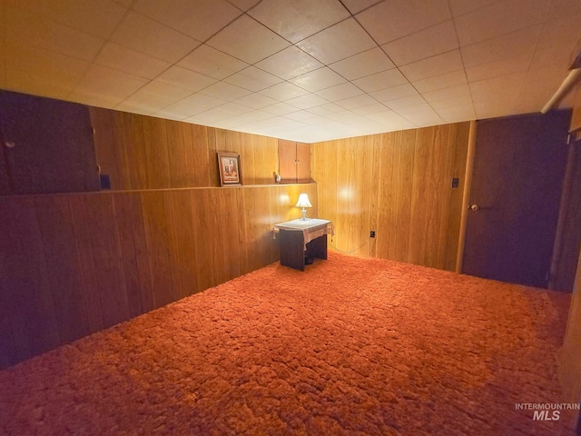 carpeted empty room featuring wood walls