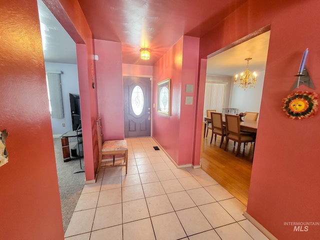 foyer entrance with light tile patterned floors, baseboards, and an inviting chandelier